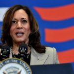 Kamala Harris speaking at a campaign rally with supporters in the background.